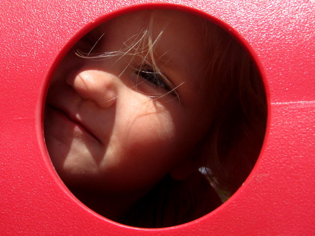 Jo Peering Through Hole at Playground Travel With Kids Playground