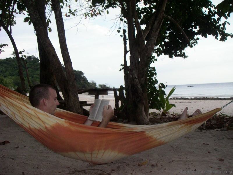 Charles Kosman reading a book in a hammock by the ocean