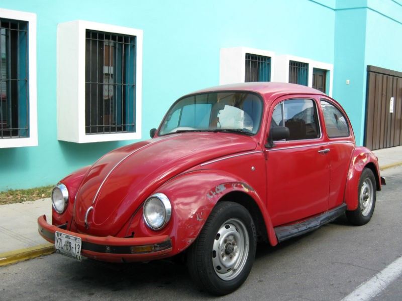 Merida Red VW Bug car Blue outside an aqua blue House