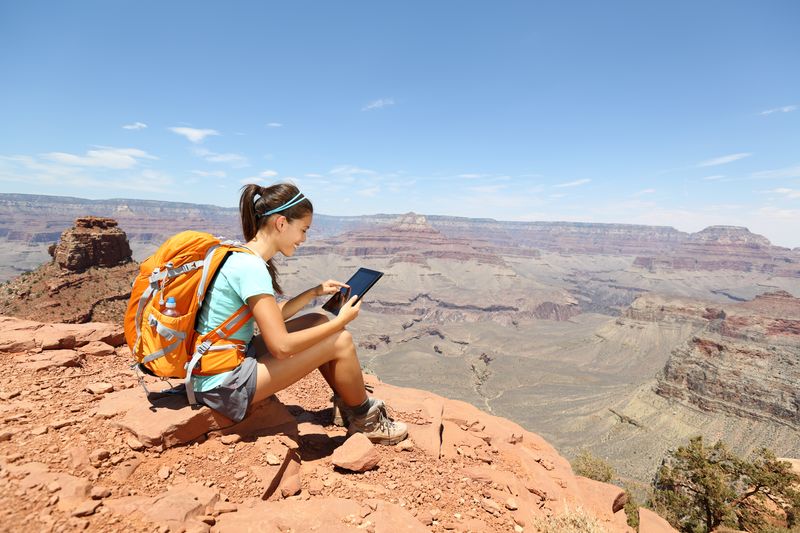 Woman hiking with a backpack and looking at a tablet