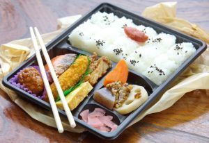 Japan Ekiben Bento box full of rice, meats and wooden chopsticks