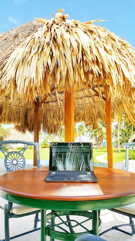 Laptop under a thatched umbrella digital nomad at work 
