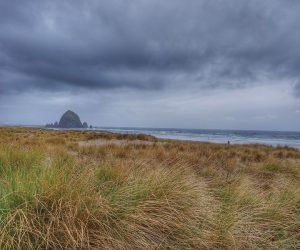 Canon beach Oregon clouds and field in front
