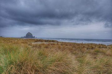 Canon beach Oregon clouds and field in front