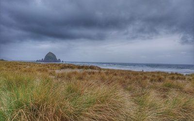 Canon beach Oregon clouds and field in front