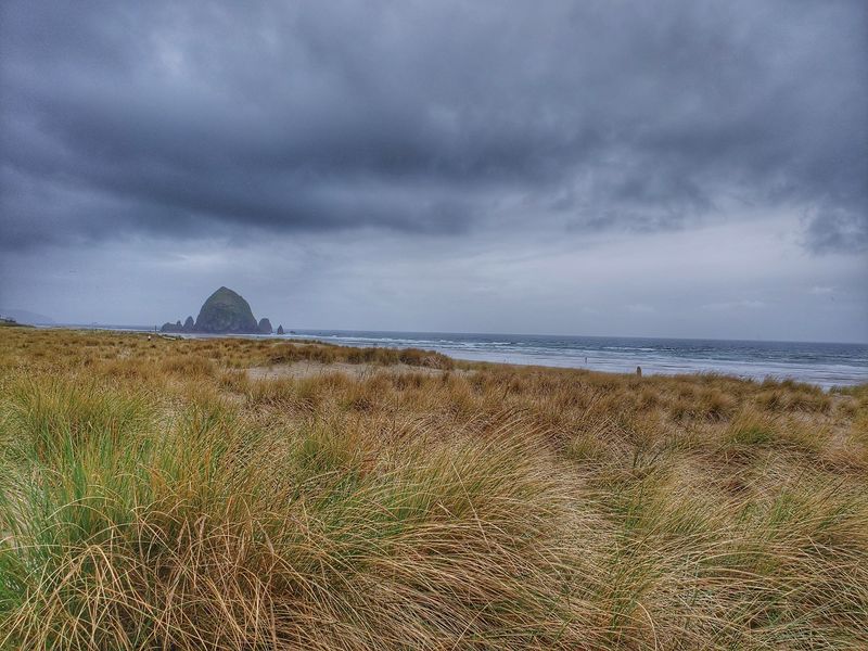 Canon beach Oregon clouds and field in front