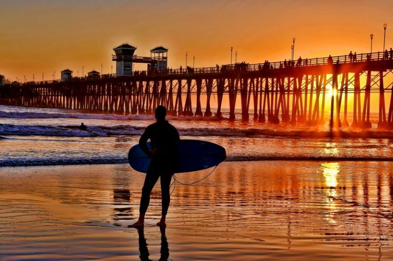 Silhouetted surfer at sunset in Oceanside California on a great weekend getaway from Los Angeles