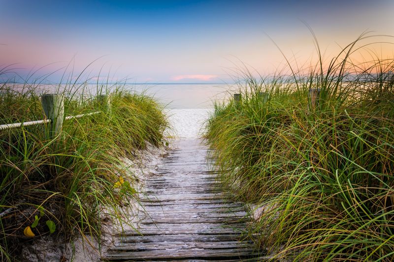 Smathers Beach at sunset with grasses and fence along wooden path One of the Best Beaches in the Florida Keys