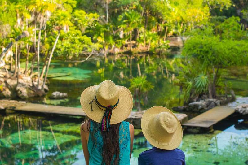 women wearing hats in front of cenote in the Mayan Riviera
