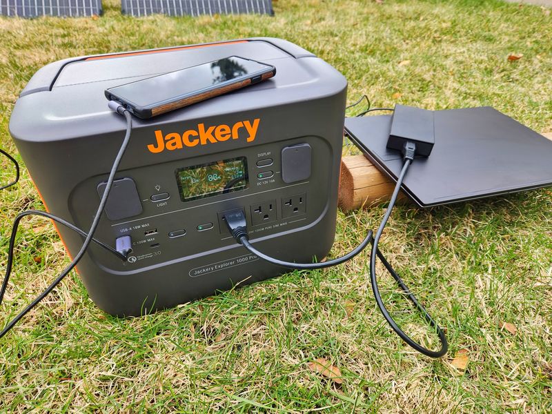 Charging laptop and phone on grass using the Jackery Explorer 1000 Pro
