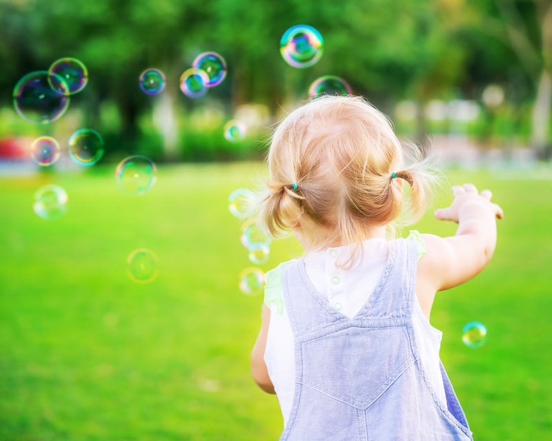 Baby girl play with soap bubbles 