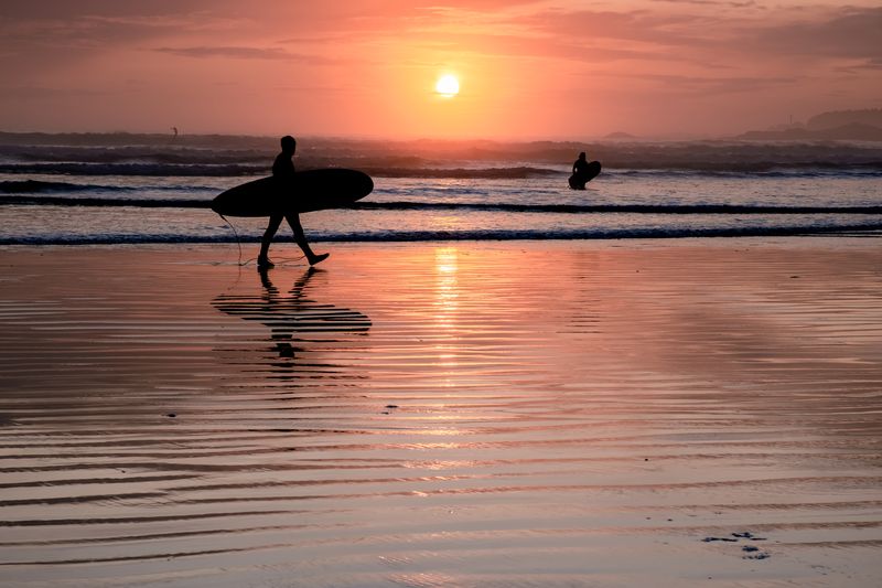 Tofino Vancouver Island Pacific rim coast, surfers with board during sunset 
