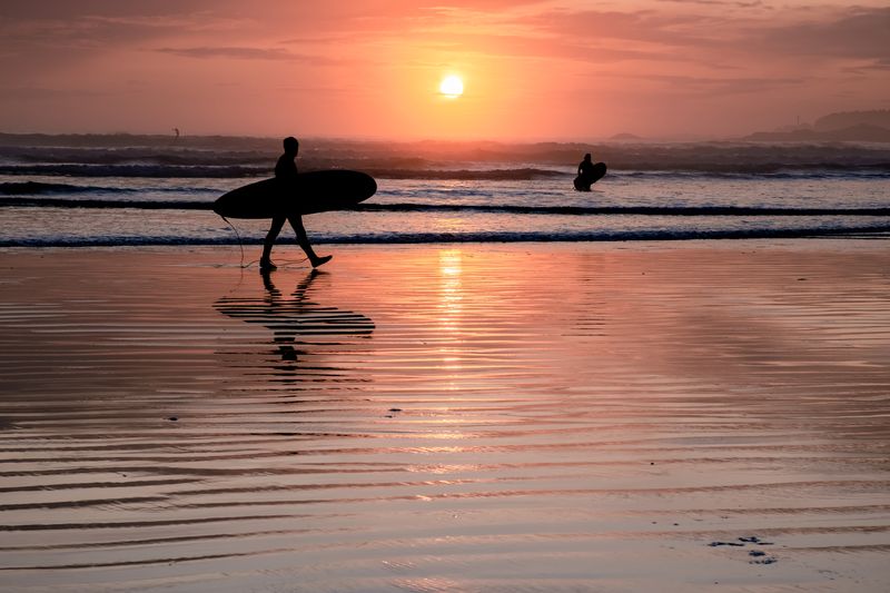 Tofino Vancouver Island Pacific rim coast, surfers with board during sunset