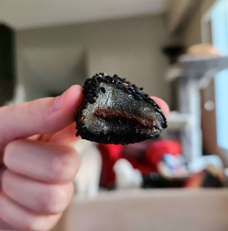 one bite Sesame Mochi inside with black sesame seeds