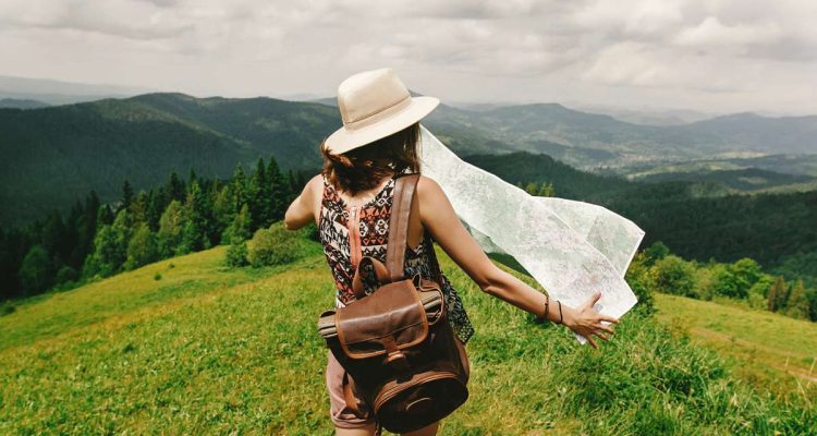 How to travel more young woman walking with hat and backpack on mountaintop