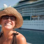 A happy woman in a hat near cruise ship