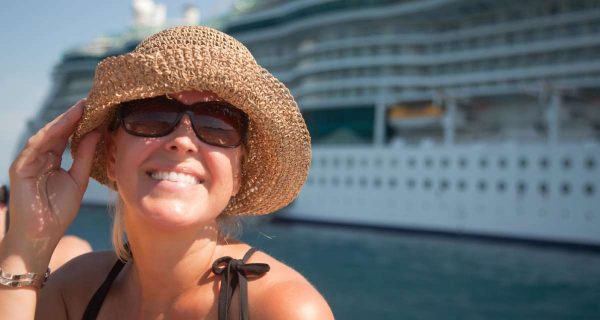 A happy woman in a hat near cruise ship