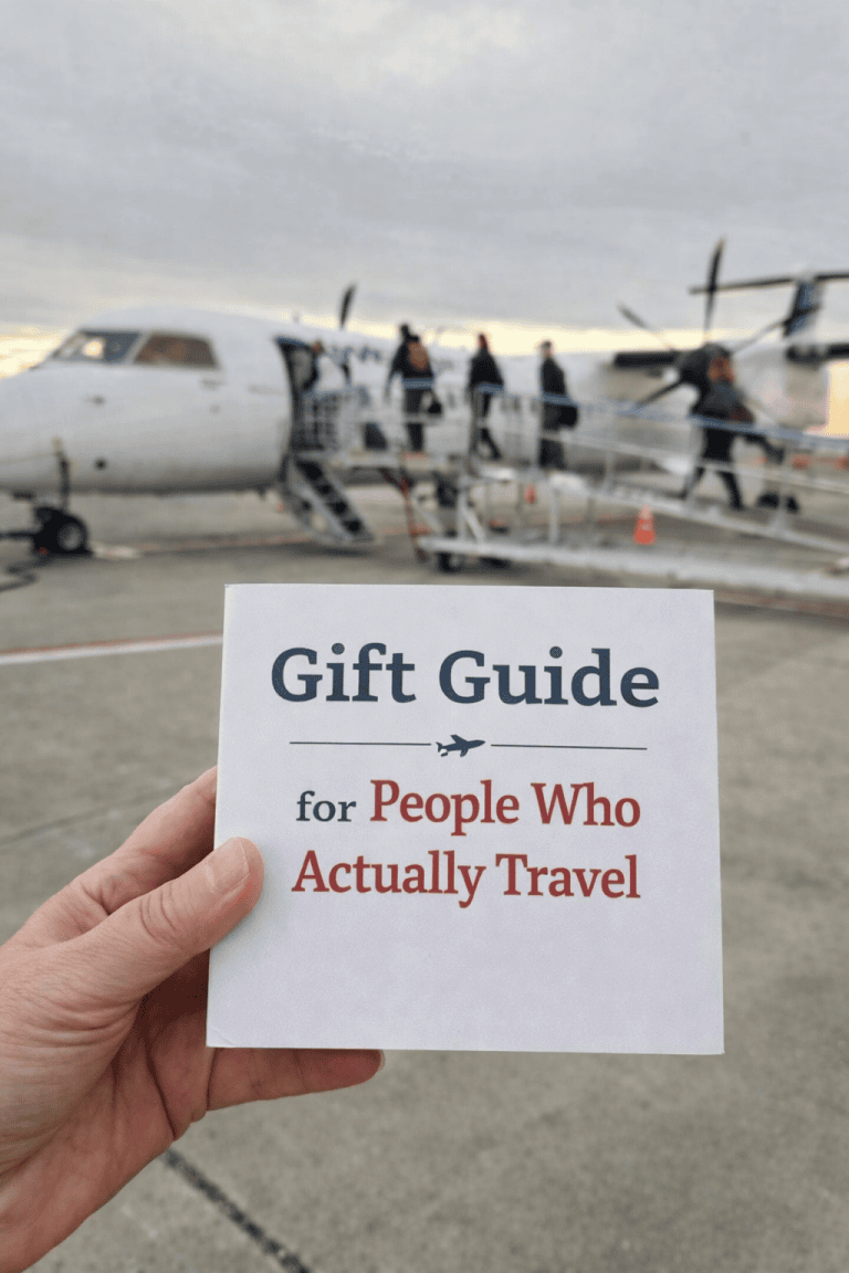 Plaque with note saying Gift Guide for People Who Actually Travel in front of a boarding plane on a runway