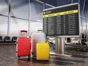 Luggage in front of cancelled flight departure board in airport