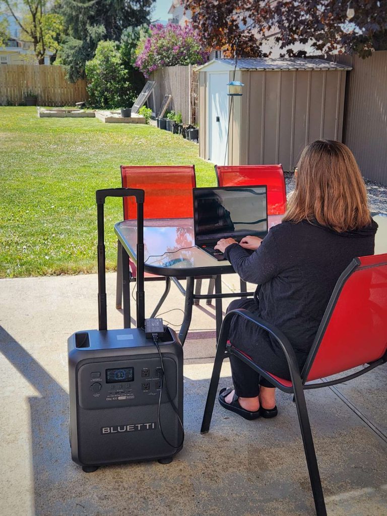 BLUETTI Elite 400 outside on patio overlooking back yard charging laptop
