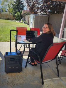 BLUETTI Elite 400 outside on patio overlooking back yard charging laptop woman smiling