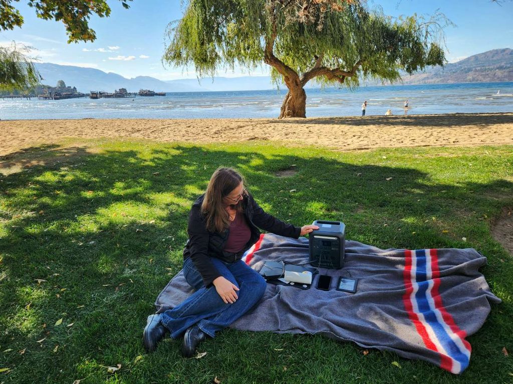 woman charging devices in park with BLUETTI Elite 100 Mini